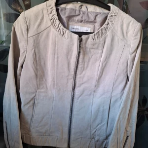 Mocka jacka från Sara Kelly - Säljer en snygg beige/grå jacka I äkta mocka från Sara Kelly. Den Perfekt för höst och vår med sin stilrena design. Jackan är i helt ny och passar till många olika outfits. 👌🥳