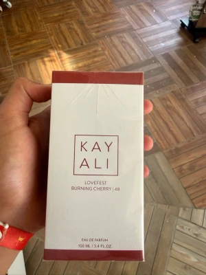 Kayali Lovefest Burning Cherry 48 EdP - Kayali Lovefest Burning Cherry 48 är en Eau de Parfum med noter av bränd körsbär, hallon, pralin, palo santo, guaiac-trä och patchouli. Flaskan rymmer 100 ml och kommer i en elegant vit och röd förpackning med stilren design.