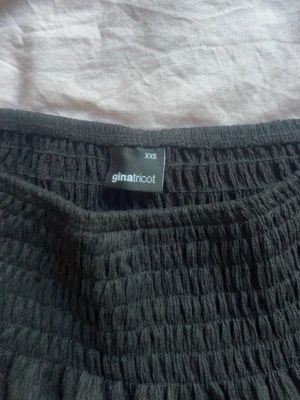Svart volangkjol från Gina Tricot - Supersöt svart kortkjol från Gina Tricot med smock i midjan och volangdetaljer. Kjolen har en luftig och flowy känsla, perfekt till sommaren eller våren. Enkel att matcha med både crop tops och stickade tröjor.