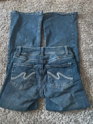 Blå bootcut jeans med broderade fickor - Säljer ett par jeans från nelly som inte kommer till användning! Använda fåtal gånger, inga defekter