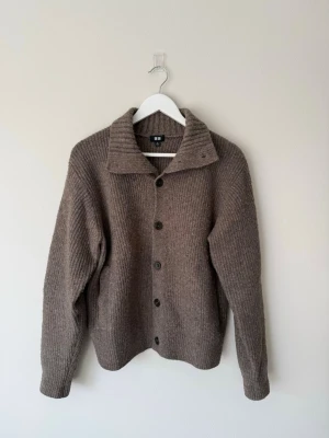 Stickad kofta från Uniqlo - Ribbstickad brun kofta från Uniqlo med bred krage och fickor. Cropped i passformen och mer som en S i storlek. Mjuk och mysig, inga hål eller fel i sömmarna! Dock har den börjat noppra, därav priset.