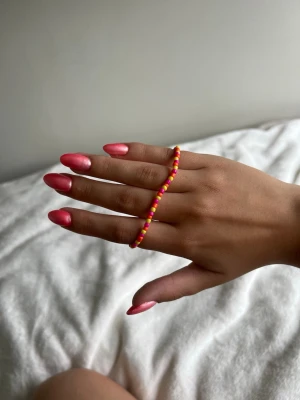 Färgglatt pärlarmband i rosa, orange och gult - Säljer ett handgjort armband med små pärlor i rosa, gult och orange. Armbandet har en tunn guldfärgad kedja och justerbart lås. Perfekt för dig som gillar färgglada accessoarer och vill addera lite extra till din stil.💕