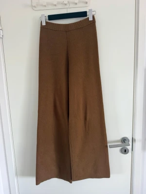 Bruna ribbade vida byxor - Säljer ett par bruna ribbade byxor med hög midja och vida ben. Materialet är mjukt och stretchigt, perfekt för en avslappnad och trendig look. Passar dig som gillar bekväma men snygga byxor med lite extra vidd. Sparsamt använda