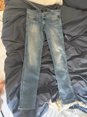 Ljusblå slim fit jeans från Replay - Snygga ljusblå slim fit jeans från Replay med klassisk femficksdesign och diskreta slitningar framtill. Jeansen har dragkedjegylf och är tillverkade i stretchigt denim för en bekväm passform. Perfekta för en avslappnad och trendig look.