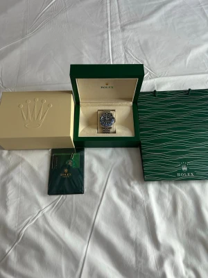 GMT-Master II Batman klocka - Säljer en GMT-Master II Batman med svart och blå vridring, svart urtavla och jubilee-länk i rostfritt stål. Klockan kommer med originalbox, certifikat och påse. En ikonisk modell för dig som gillar exklusiva accessoarer.