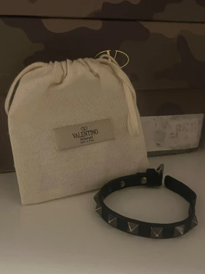 Valentino armband - Säljer nu mitt äkta valentino armband då jag använder ett annat armband just nu mer. Justerbar storlek så passar nog typ alla. Allt på bilderna medkommer, (valentino påse, kort, extra nitar) Skick 7/10 inga defekter förutom tecken på användning! Unikt och snyggt armband. 