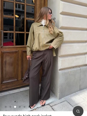 Beige oversized skinnjacka - Snygg beige oversized skinnjacka med hög krage och dragkedja framtill. Jackan har justerbara spännen i midjan och raka ärmar. Perfekt för dig som gillar en avslappnad men trendig stil.