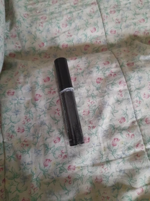 Svart mascara med smal tub - En klassisk svart mascara i en smal, cylinderformad tub med svart lock. Perfekt för att framhäva fransarna och skapa en intensiv blick. Tuben är tillverkad i plast och har en stilren, enkel design.