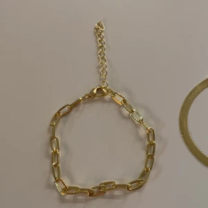Guldigt armband  - Armbandet är 15 cm med 5 cm tillägg. Aldrig använt säljer då det är för stort. 