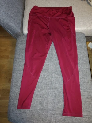 Mörkröda träningstights med hög midja - Snygga mörkröda träningstights med hög midja och smickrande sömmar. Stretchigt material som sitter tajt och bekvämt. Perfekta för träning eller chill. Inga synliga loggor eller märken.
