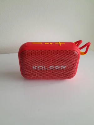 Röd bärbar högtalare med gult band - Lyft din ljudupplevelse ​Ta med dig musiken överallt med den helt nya bärbara trådlösa högtalaren Koleer H73. Genom att kombinera en livfull röd finish med en kompakt och robust design levererar den här högtalaren en imponerande ljudprestanda som överträffar förväntningarna för sin storlek. Oavsett om du hänger hemma, cyklar eller spenderar en dag utomhus är den designad för att hålla stämningen på topp. ​Huvudfunktioner & Specifikationer ​Kraftfullt ljud: Utrustad med 8W uteffekt för fyllig bas