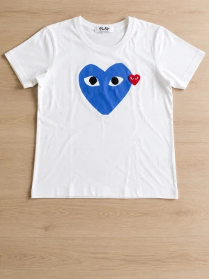 Vit t-shirt Comme des Garçons Play - Vit t-shirt från Comme des Garçons Play med ett stort blått hjärta med ögon och ett litet rött hjärta på bröstet. Klassisk rund hals och korta ärmar. Tillverkad i mjuk bomull för en bekväm känsla.