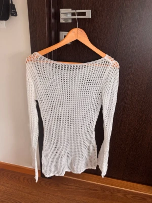 Vit virkad cover upp med lång ärm - Vit virkad cover up med lång ärm och rundad hals. Perfekt att dra över bikinin på stranden för en avslappnad och trendig look. Luftigt material som ger en bohemisk känsla. XS - S