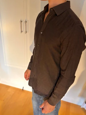 Mörkbrun skjorta från Boss - Snygg mörkbrun skjorta med klassisk krage och knäppning framtill. Skjortan har lång ärm och en rak passform, perfekt att styla med jeans eller chinos. Sitter som en medium. 100% bomull.