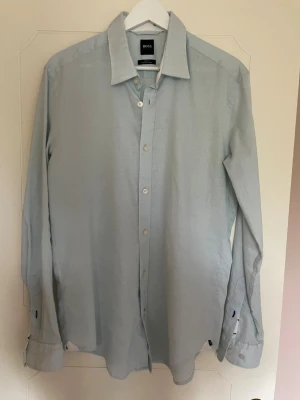 Ljusblå linneskjorta från Hugo Boss - Snygg ljusblå skjorta från Hugo Boss i stretchigt linne. Skjortan har slim fit-passform och storlek M.