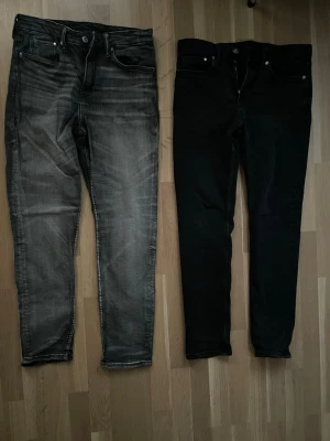 Två par Slim Jeans från HM, svart & grå. Storlekar 32 - Säljer två par slim jeans, ett par i tvättad grå och ett par i helsvart. Båda har klassisk femficksdesign. Säljer båda till ett billigare pris om man vart intresserad i bägge två.