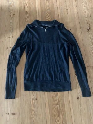 Mörkblå stickad tröja Jack & Jones - Mörkblå stickad tröja från Jack & Jones med halv dragkedja vid halsen. Tröjan har lång ärm, ribbade muddar och en stilren, enkel design. Perfekt för lager på lager och passar till det mesta. Materialet är mjukt och bekvämt.