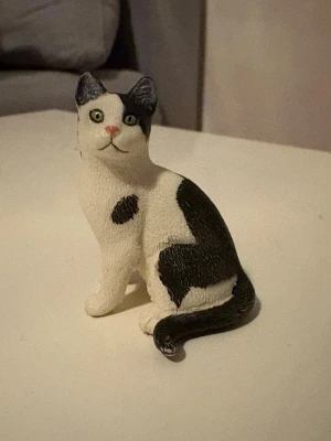 Schleich Kart - Säljer en söt kattfigur i svart och vitt. Figuren är gjord i plast och har detaljerade drag med gröna ögon och rosa nos. Perfekt som dekoration till skrivbordet eller hyllan för dig som gillar katter.