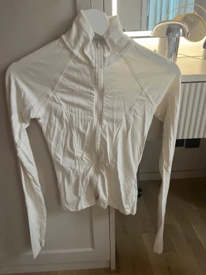 Vit ziptröja från Gina Tricot XS - Säljer en vit ziptröja från Gina Tricot i storlek XS. Tröjan har hög krage, långa ärmar och dragkedja framtill. Perfekt för lager på lager och enkel att matcha med olika outfits.