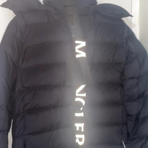 Mörkblå dunjacka från Moncler - Snygg och varm mörkblå dunjacka från Moncler med dragkedja och huva. Perfekt för kyliga dagar med sin quiltade design och långa ärmar. Moncler-logga synlig på framsidan. Storlek M passar L pris kan diskuteras 