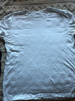 Vit t-shirt från GANT - Klassisk vit t-shirt från GANT med diskret logga broderad på bröstet. T-shirten har rund halsringning och är tillverkad i mjukt bomullstyg. Perfekt basplagg som funkar till allt och är enkel att matcha.