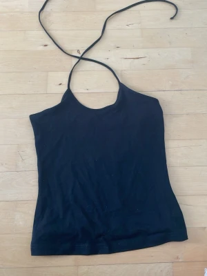 Svart halterneck topp - Säljer en svart halterneck topp från weekday med smala knytband i nacken. Den är köpt i mars men har aldrig använt den. Jag är 175 och har M eller S i storlek på tröjor. Pris kan diskuteras fråga ifall du undrar något☺️