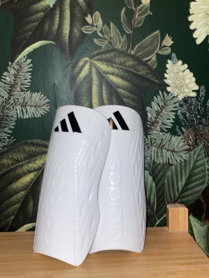 Vita benskydd från Adidas - Säljer nu mina adidas benskydd. Det är adidas tiro club benskydd och är storlek S tror jag. Rengjort de så gott jag kan men kan vara nåt smuts. Det är bara och skriva om ni undrar något. Barnstorlek!