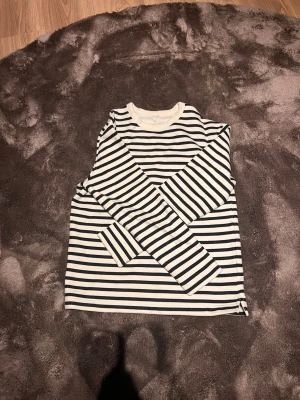 Randig långärmad tröja - Snygg långärmad tröja med klassiska svarta och vita horisontella ränder. Tröjan har rund halsringning och är gjord i ett mjukt, bekvämt material. Perfekt för en avslappnad och stilren look. Storlek xs-s sitter mer som s 