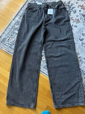 Gråa baggy jeans med raka ben - Storlek 32/34 , baggy, mid waist, loose fit.    Säljer ett par gråa baggy jeans med raka, vida ben och klassisk femficksmodell. Jeansen har hög midja och stängs med knapp och dragkedja. Perfekta för en avslappnad och trendig stil. Materialet är denim i bomull.