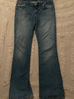 Valerie roxy jeans - Ett par klassiska blå bootcut jeans med låg midja och fem fickor från valerie i modellen roxy. Jeansen har en lätt tvättad look och vida ben från knät och ner. 