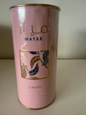 Lattafa, Mayar parfym från Lattafa 100ml - Helt ny, köpt på Norillo. Säljer en Mayar parfym från Lattafa i en snygg rosa och guldig cylinderförpackning med bladmotiv. Flaskan rymmer 100 ml Eau de Parfum och har eleganta detaljer i guld och blått. Perfekt för dig som gillar exklusiva dofter och stilren design.