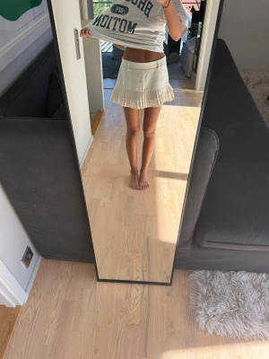 Vit plisserad kortkjol - Snygg vit kortkjol med plisserad nederkant. Kjolen har en klassisk och fräsch look som passar perfekt till sommaren. Den är enkel att matcha med olika toppar och ger en sportig vibe.