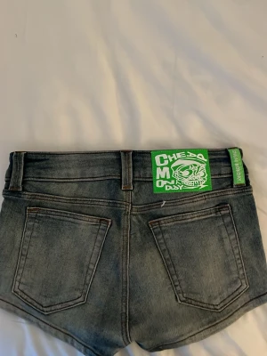 Blå denimshorts med fem fickor - Snygga blå denimshorts i klassisk femficksmodell med bälteshällor och knappstängning. Shortsen har en något urtvättad look och är korta i modellen. Perfekta för varma dagar och enkla att matcha med olika toppar.