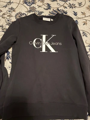  Calvin Klein - En svart sweatshirt med en vit logga imitten från Calvin Klein perfekt för dig som vill ha en avslappnad look
