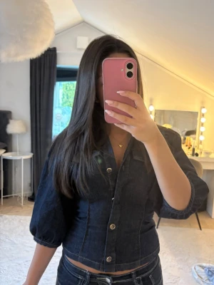 Mörkblå jeansblus med puffärm - Snygg mörkblå jeansblus med puffiga trekvartsärmar och markerad midja. Blusen har knappar framtill och en klassisk krage. Perfekt för dig som gillar en trendig och stilren look med denimkänsla💕💕