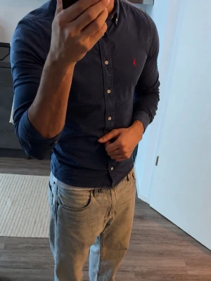 Ralph Lauren Skjorta - Snygg mörkblå skjorta från Polo Ralph Lauren med klassisk krage och knappar framtill. 