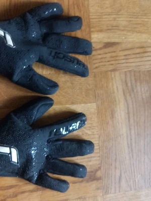 Svarta målvaktshandskar med grepp - Säljer ett par svarta målvaktshandskar med greppig yta och vita detaljer. Perfekta för dig som gillar fotboll och vill ha bra kontroll på bollen. Handskarna har en sportig look och sitter skönt på handen. Bara att höra av vid funderingar