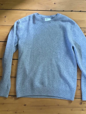 Colorful standard crewneck - En stilren ljusgrå stickad tröja med rund halsringning och ribbade muddar vid ärmslut och nederkant. Tröjan har en klassisk passform och är tillverkad i mjuk merinoull perfekt för kyligare dagar. Nypris 1200kr. Knappt använd. Tveka inte att ställa frågor.