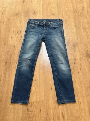 Blå Jacob cohen - Säljer ett par blå jeans från Jacob Cohën med snyggt slitna detaljer och raka ben. Jeansen har klassisk femficksmodell, knappgylf och kontrastsömmar. Perfekta för en avslappnad och trendig look.