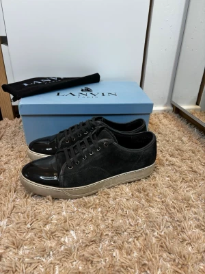 Lanvin sneakers - Snygga sneakers från Lanvin med ovandel i mocka och lackad tå.  Perfekta för dig som gillar stilrena och exklusiva detaljer. Kommer med originalkartong.