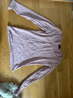 Ljusrosa långärmad topp - En enkel och mjuk ljusrosa långärmad topp med rund halsringning. Tillverkad i ett tunt och bekvämt bomullsmaterial som passar perfekt till jeans eller kjol. Snygg bas i garderoben för dig som gillar en clean och avslappnad stil.