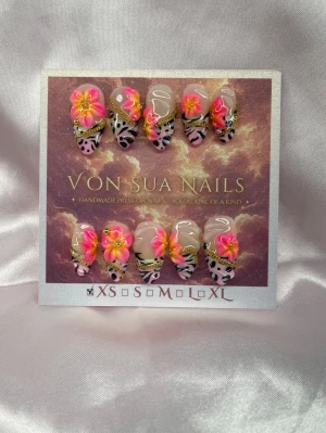 FrankieSoft (XS):Medium Almond - Unika handgjorda press-on naglar med handmålat tiger-leopardmönster, 3D-blommor i rosa och gult samt gulddetaljer. Naglarna har en medium lång almondform och en nude bas med kreativa detaljer som verkligen sticker ut.XS: 14 mm, 11 mm, 11,5 mm, 10 mm, 8 mm. Inspo av konstnären Lisa Frank.