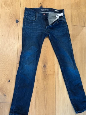 Mörkblå slim fit jeans - Snygga mörkblå slim fit jeans med klassisk femficksdesign och kontrastsömmar. Jeansen har en smal passform och är tillverkade i stretchigt denimtyg för extra komfort. Perfekta för dig som gillar en modern och stilren look.  W:31 L:32