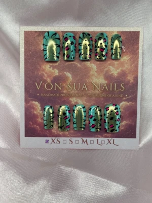 Slash (XS);Short Square - Unika handgjorda press-on naglar i turkos och guld med handmålat svart och rosa tiger/leo mönster. Naglarna har en kort square, med finish och varierar mellan metallic och pastelltoner. Perfekt för dig som vill sticka ut med kreativa och färgstarka naglar.XS: 14 mm, 11 mm, 11,5 mm, 10 mm, 8 mm