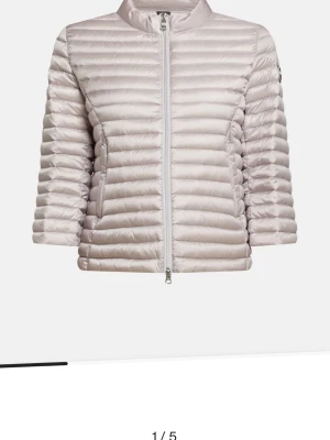 Ljusgrå dunjacka med trekvarts ärm - Snygg ljusgrå dunjacka med horisontella sömmar och 3/4-ärm. Jackan har en hög krage och dragkedja framtill. Perfekt för kalla vinterdagar och ger en stilren look.HELT NY. Hör av vid intresse av bild elrlr något 💕