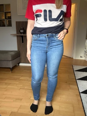Blå raka jeans med fem fickor - Snygga blå jeans med klassisk femficksmodell och raka ben. Jeansen har en lätt tvättad look med subtila slitningar framtill och stängs med knapp och dragkedja. Perfekta till vardagsstilen och passar till det mesta. Materialet är denim i bomull.