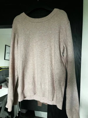 Beige stickad tröja från VILA - Mysig beige stickad tröja från VILA med rund halsringning och ribbade muddar vid ärmslut och nederkant. Perfekt för lager på lager och enkel att matcha med jeans eller kjol. Materialet känns mjukt och skönt mot huden.