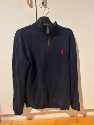 Mörkblå half-zip tröja från Polo Ralph Lauren - Säljer en schysst quarter zip av Ralph Lauren. Perfekt inför hösten/vintern och en väldigt bekväm tröja. Skicka pm vid funderingar😊🙌