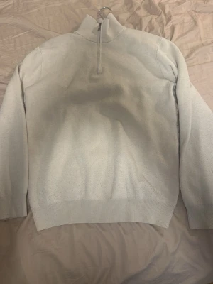 Beige halvzip tröja - En stilren beige tröja med halv dragkedja och hög krage. Tröjan har långa ärmar och ribbade muddar vid ärmslut och nederkant. Perfekt för lager på lager och enkel att matcha med olika outfits.