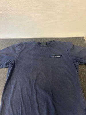 Mörkblå Peak Performance t-shirt - Snygg mörkblå t-shirt från Peak Performance med diskret logga på bröstet. Klassisk rund halsringning och korta ärmar. Tillverkad i mjuk bomull som känns skön mot huden. Perfekt för en avslappnad och stilren look.
